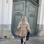modna dziewczyna w bezowej kurtce idzie do biura