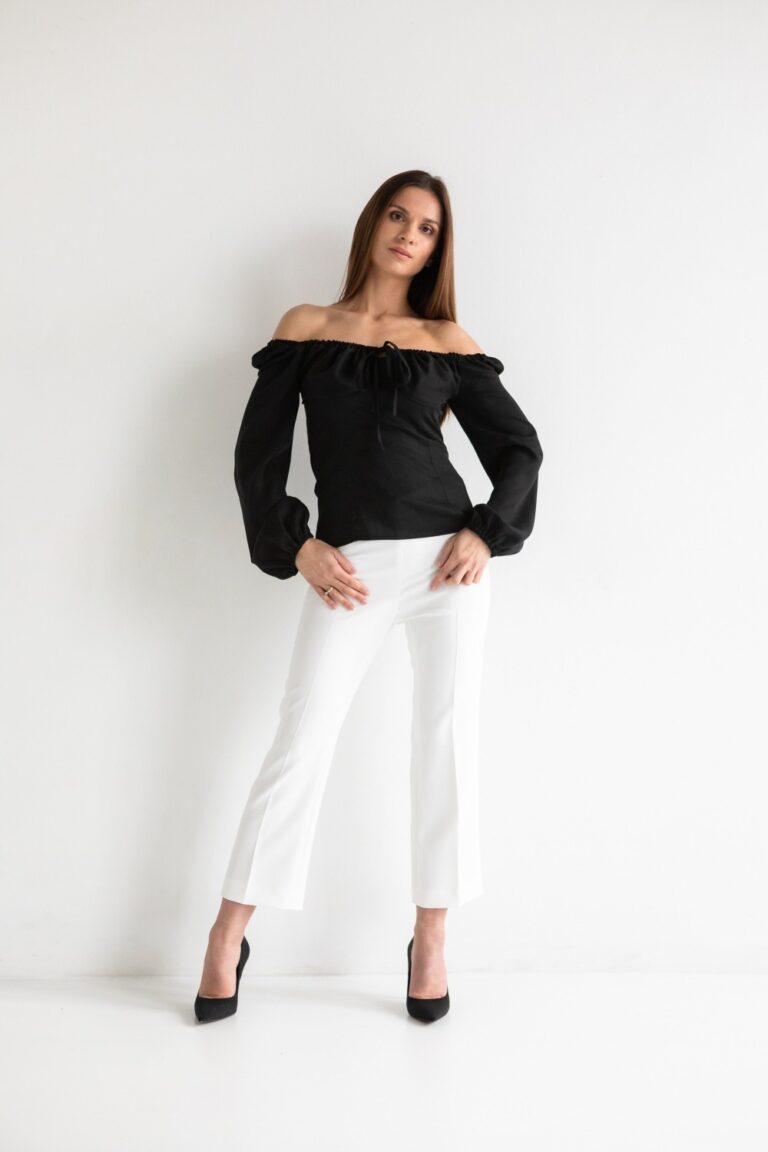 elegancka kobieta w czarnej bluzce białych spodniach i czarnych szpilkach